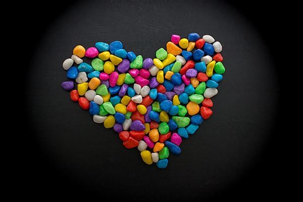 Colorful little pebbles form heart shape on black