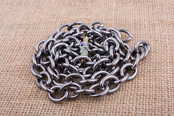 Woman figurine on steel chains on a textured surface on display