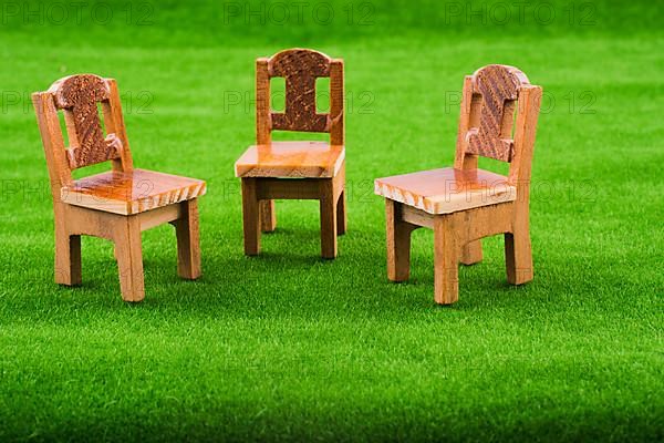 Brown color wooden toy chair on artificial grass
