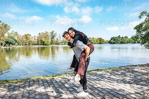 Happy couple. Handsome young man carrying his beautiful girlfriend on his back. They are looking at camera