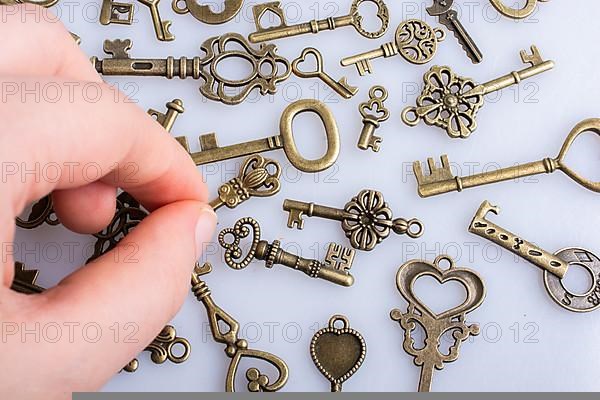 Hand and retro style metal keys on a white background