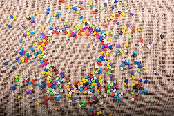 Colorful little pebbles form a heart shape on canvas ground