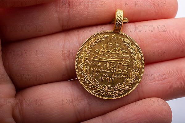 Turkish Ottoman style gold coin in hand on white background