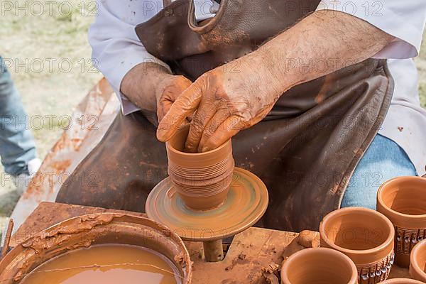 Potter's hands shaping up the clay of the pot