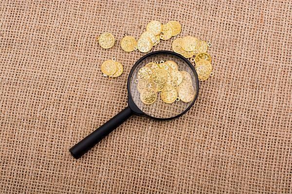 Plenty of fake gold coins behind magnifying glass