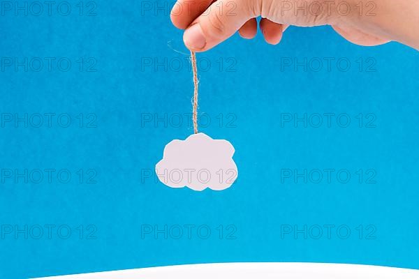 Hanging cloud held by a hand on a blue background