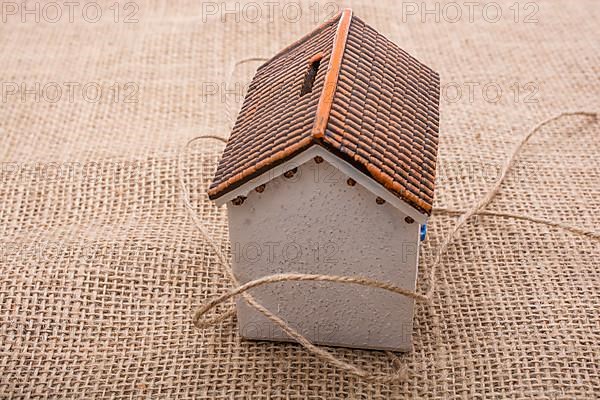 Thread wrapped around a model house on a brown background