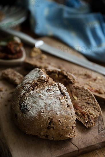 Freshly baked bread with walnuts and pickled tomatoes on a wooden board