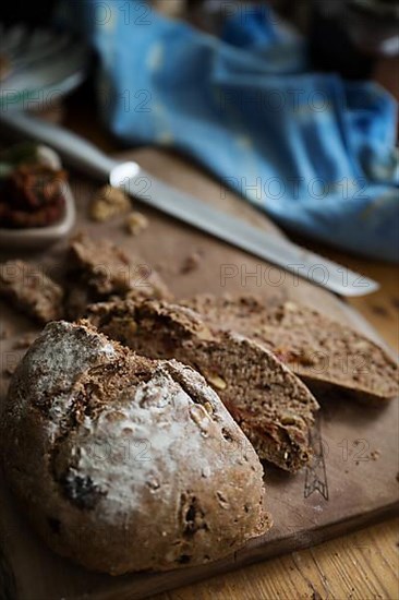 Freshly baked bread with walnuts and pickled tomatoes on a wooden board