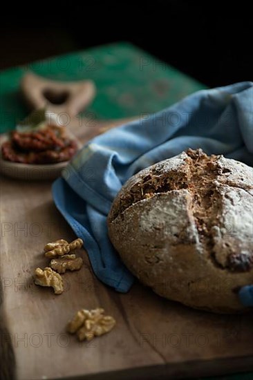 Freshly baked bread with walnuts and pickled tomatoes on a wooden board