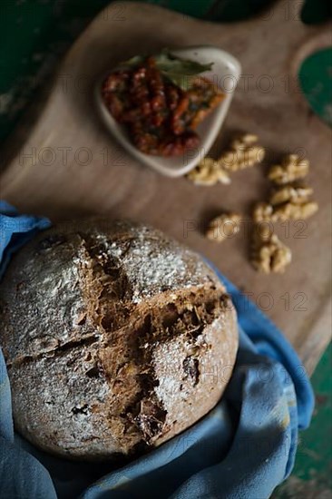 Freshly baked bread with walnuts and pickled tomatoes on a wooden board