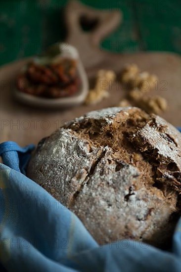 Freshly baked bread with walnuts and pickled tomatoes on a wooden board