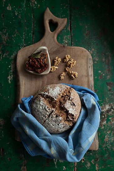 Freshly baked bread with walnuts and pickled tomatoes on a wooden board