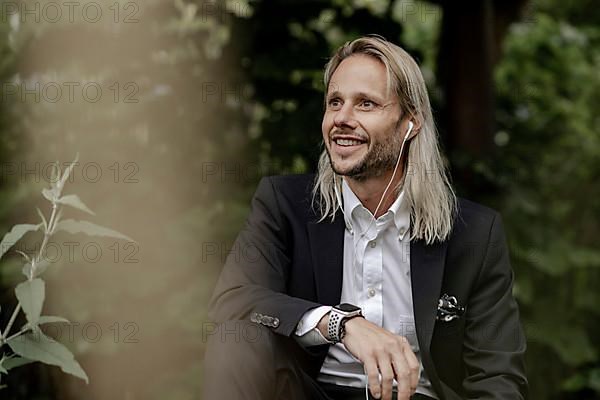 Blond businessman with headset in the countryside,