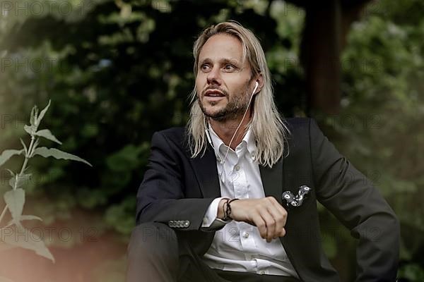 Blond businessman with headset in the countryside,