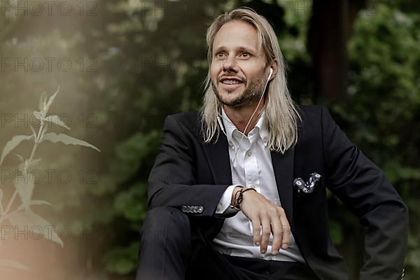 Blond businessman with headset in the countryside,