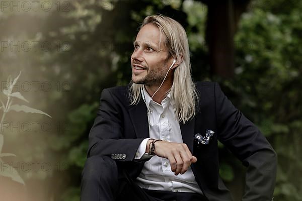 Blond businessman with headset in the countryside,