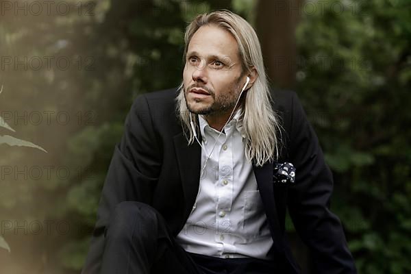 Blond businessman with headset in the countryside,