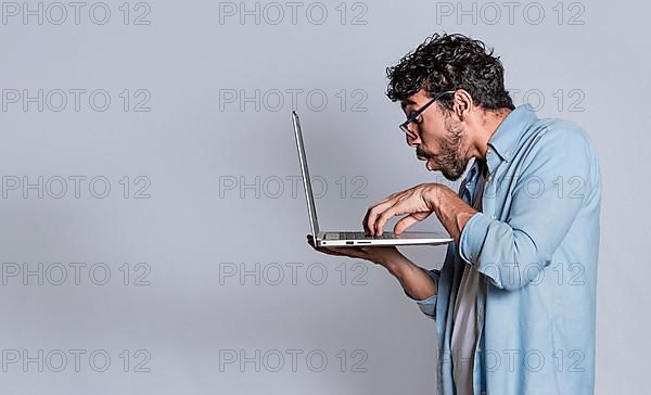 Amazed handsome man with laptop isolated. Surprised person looking at an offer on laptop, surprised people looking at a promotion on laptop isolated