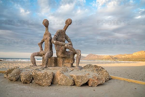 Sculptures by Joan Bennassar on beach promenade with sandy beach Playa Sa Canova in Son Serra de Marina, Serres de Llevant mountains in the back