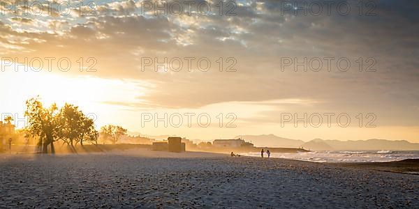 Evening atmosphere at the sandy beach playa in Son Serra de Marina, Tramuntana Mountains in the back