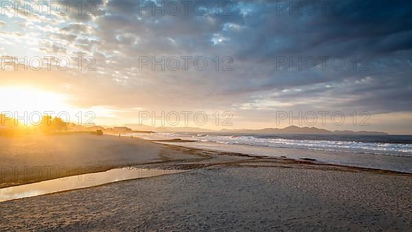 Sunset at the sandy beach playa in Son Serra de Marina, Tramuntana Mountains in the back