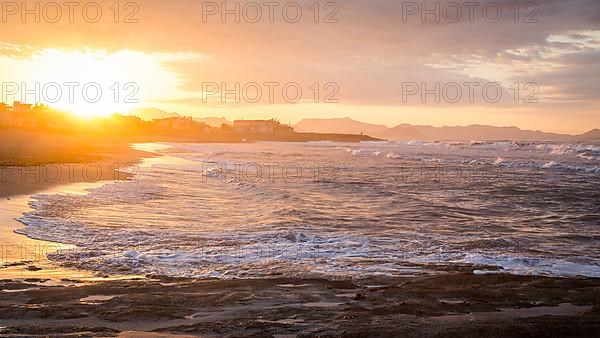 Sunset at the sandy beach playa in Son Serra de Marina, Tramuntana Mountains in the back