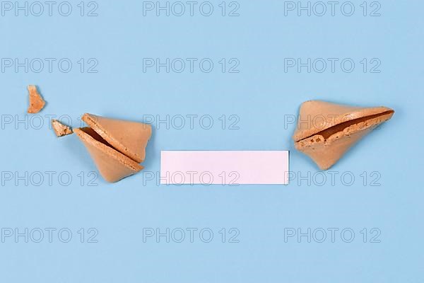 Open fortune cookie with note without text on blue background,