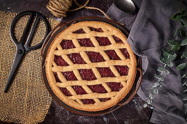 Top view of homemade pie called Linzer Torte, a traditional Austrian shortcake pastry topped with fruit preserves and sliced nuts with lattice design