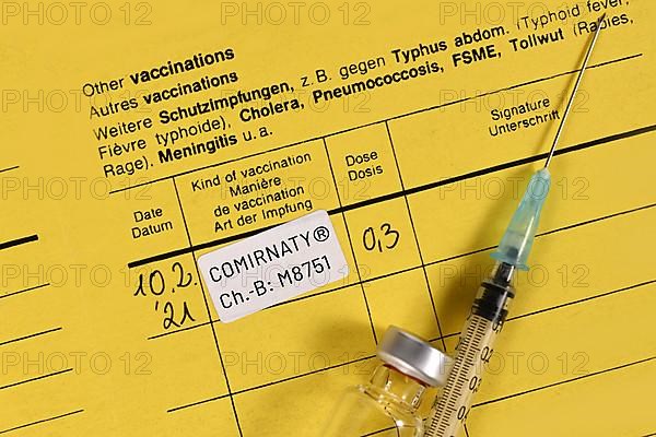 Germany, February 2020: Certificate of vaccination with Pfizerâ€“BioNTech COVID-19 vaccine Comirnaty with syringe and vial