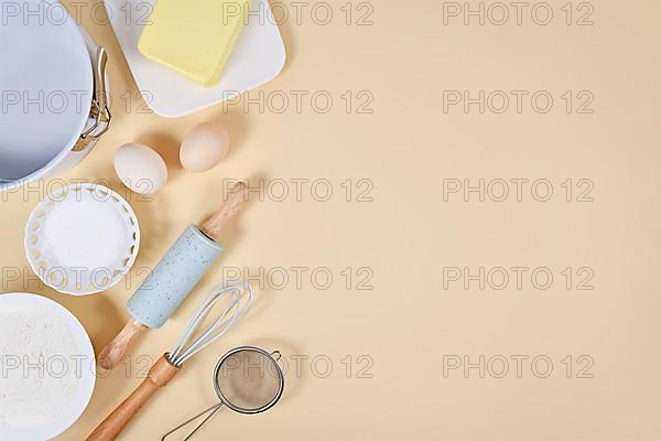 Cake dough ingredients and baking tools on beige background with copy space,
