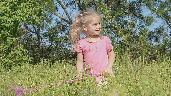 Little girl plays with butterfly net of tall grass in city park. Cute little girl is playing with aerial insect net in meadow on sun day. Odessa, Ukraine