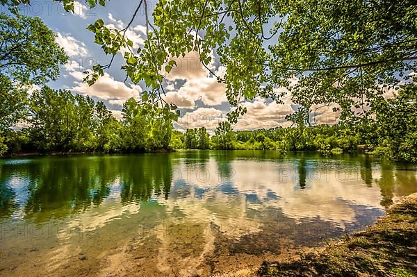 View over the gravel pond in Lohnde with blue sky and scattered clouds, Seelze