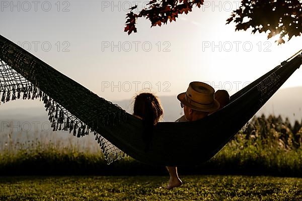 Couple lying in a hammock at sunset, Carinthia