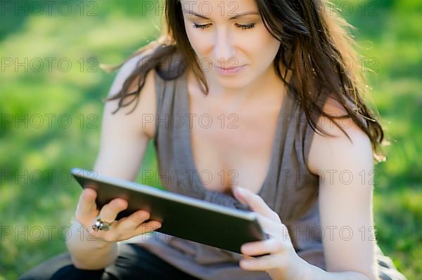 Woman with tablet sitting in meadow,