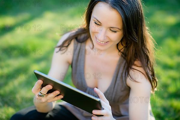 Woman with tablet sitting in meadow,