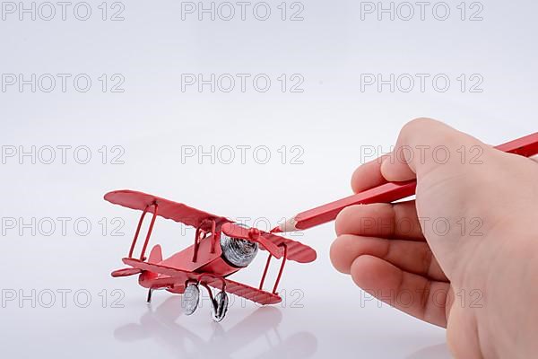 Red color pen in touch with little metal model airplane,
