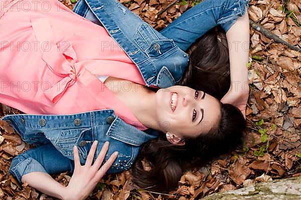 Young woman lying on the forest floor,