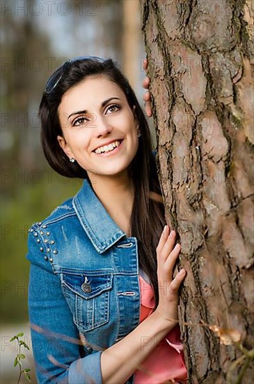 Woman leaning against tree trunk,