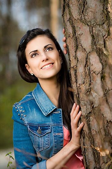 Woman leaning against tree trunk,