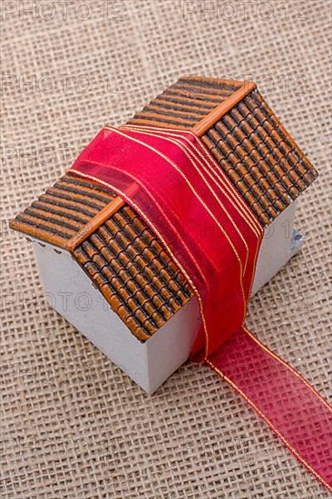 Pink band wrapped around a model house on a brown background,