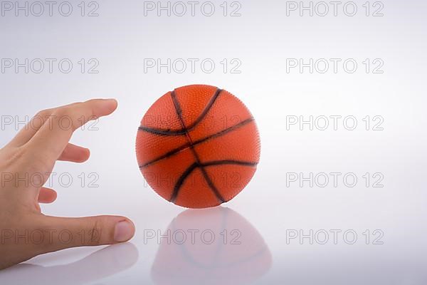 Hand holding an orange basketball model on a white background,
