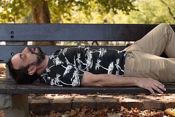 A man sleeping on a bench at the park,