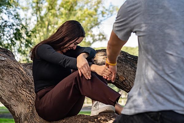 Young man takes the hand of a beautiful girl asking her to go with him. She laughs and seems to be happy,