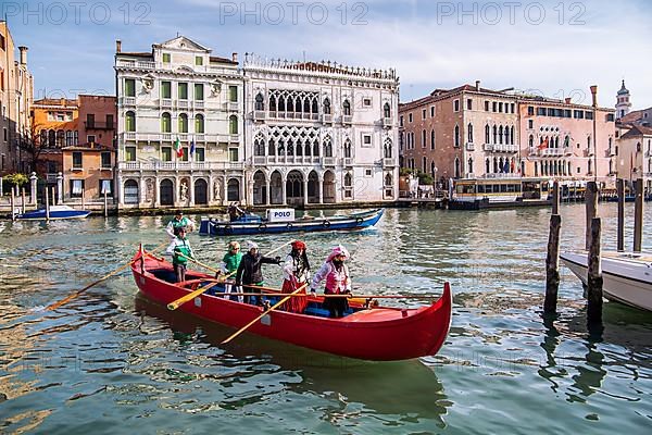 Rowing boat with carnival masks in front of Palazzo Ca dOro on the Grand Canal, Venice