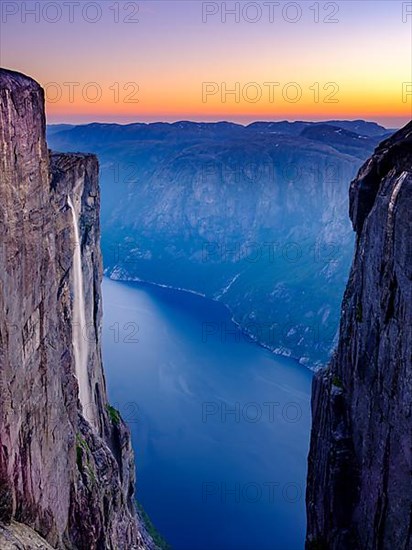 Waterfall cascading over the rocks of Kjerag into Lysefjord at dusk, Lyseboten