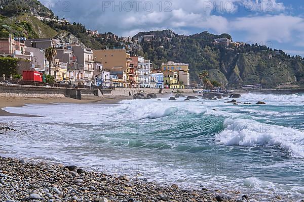 Sea surf in front of the promenade with Taormina on the hill, Giardini-Naxos