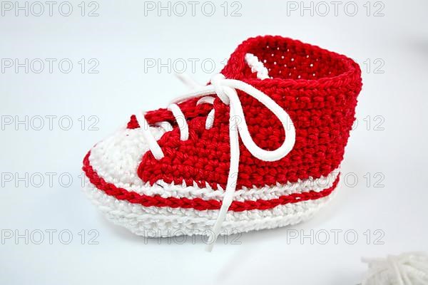 Baby shoes or crochet shoes in red and white isolated against a white background,