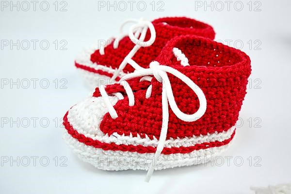 Baby shoes or crochet shoes in red and white isolated against a white background,