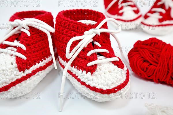 Baby shoes or crochet shoes in red and white isolated against a white background,